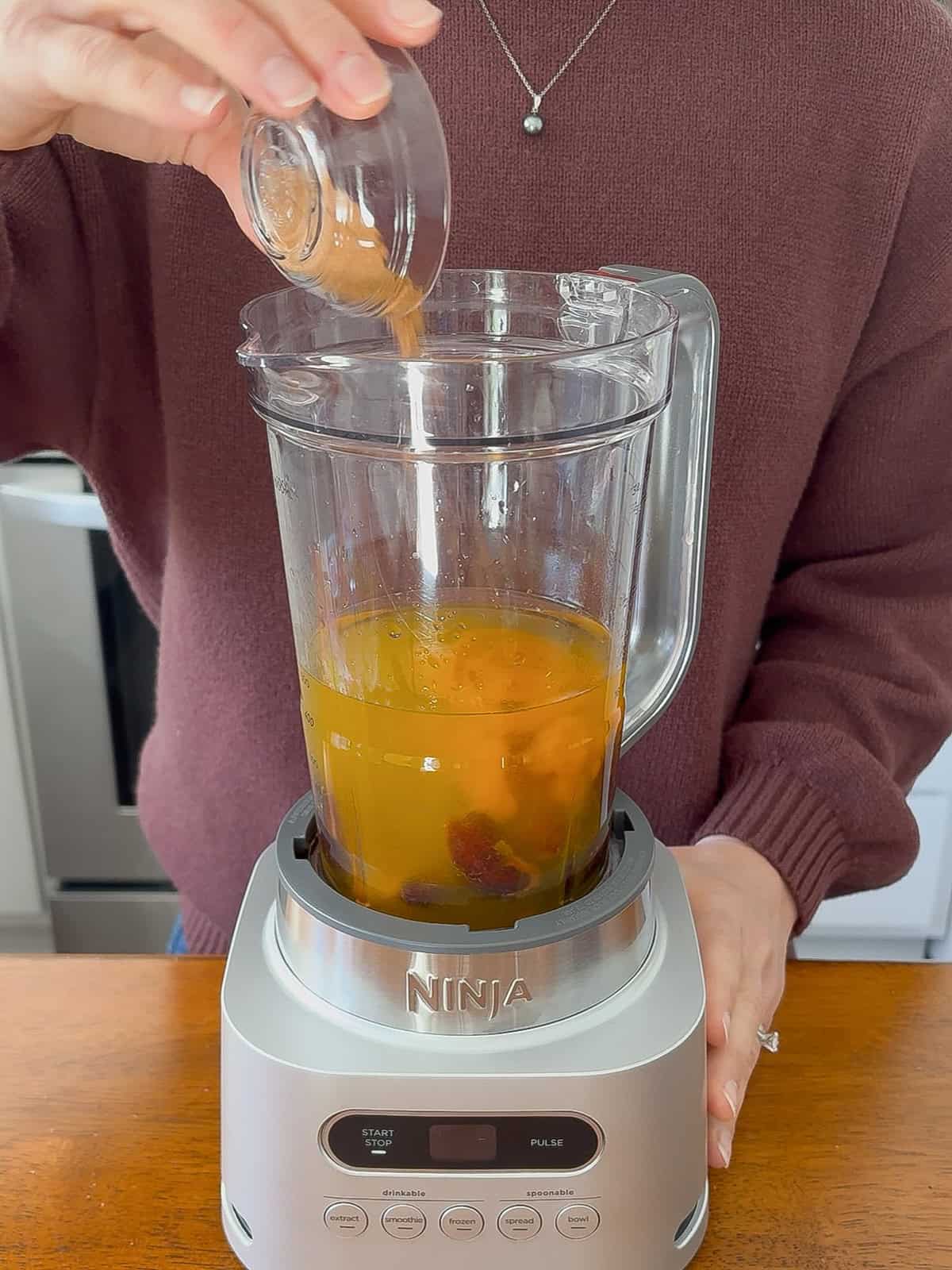 Adding pumpkin pie spice to the blender.