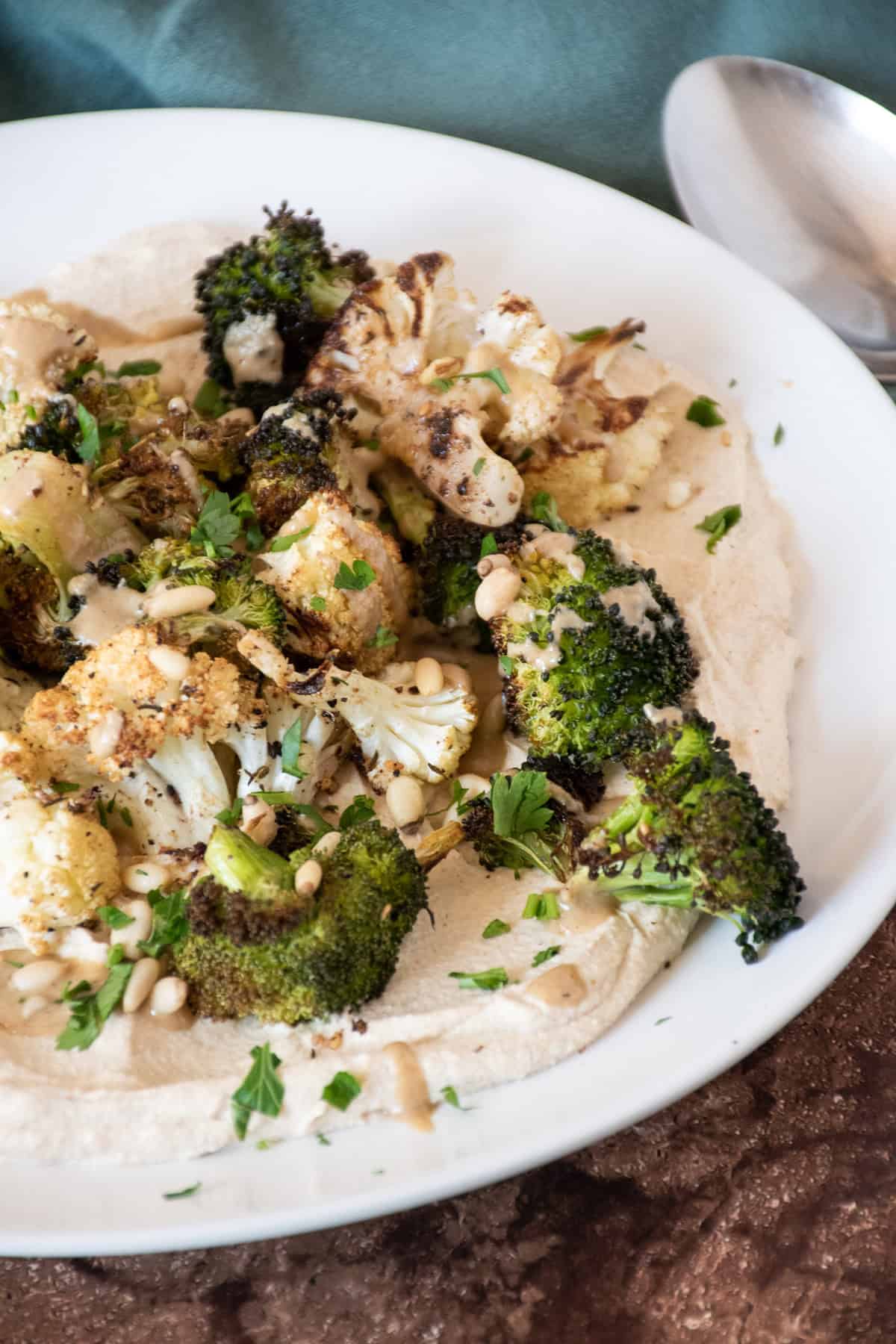 Roasted broccoli and cauliflower on a plate, over whipped tofu.