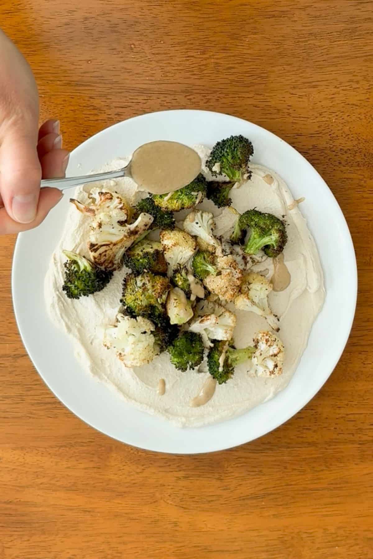 Tahini being drizzled over the dish.