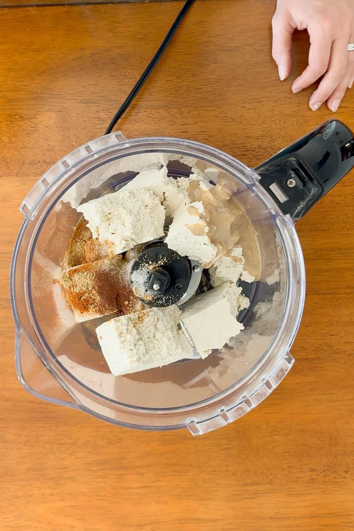 Spices, tahini, and lemon juice added to the tofu in the food processor.