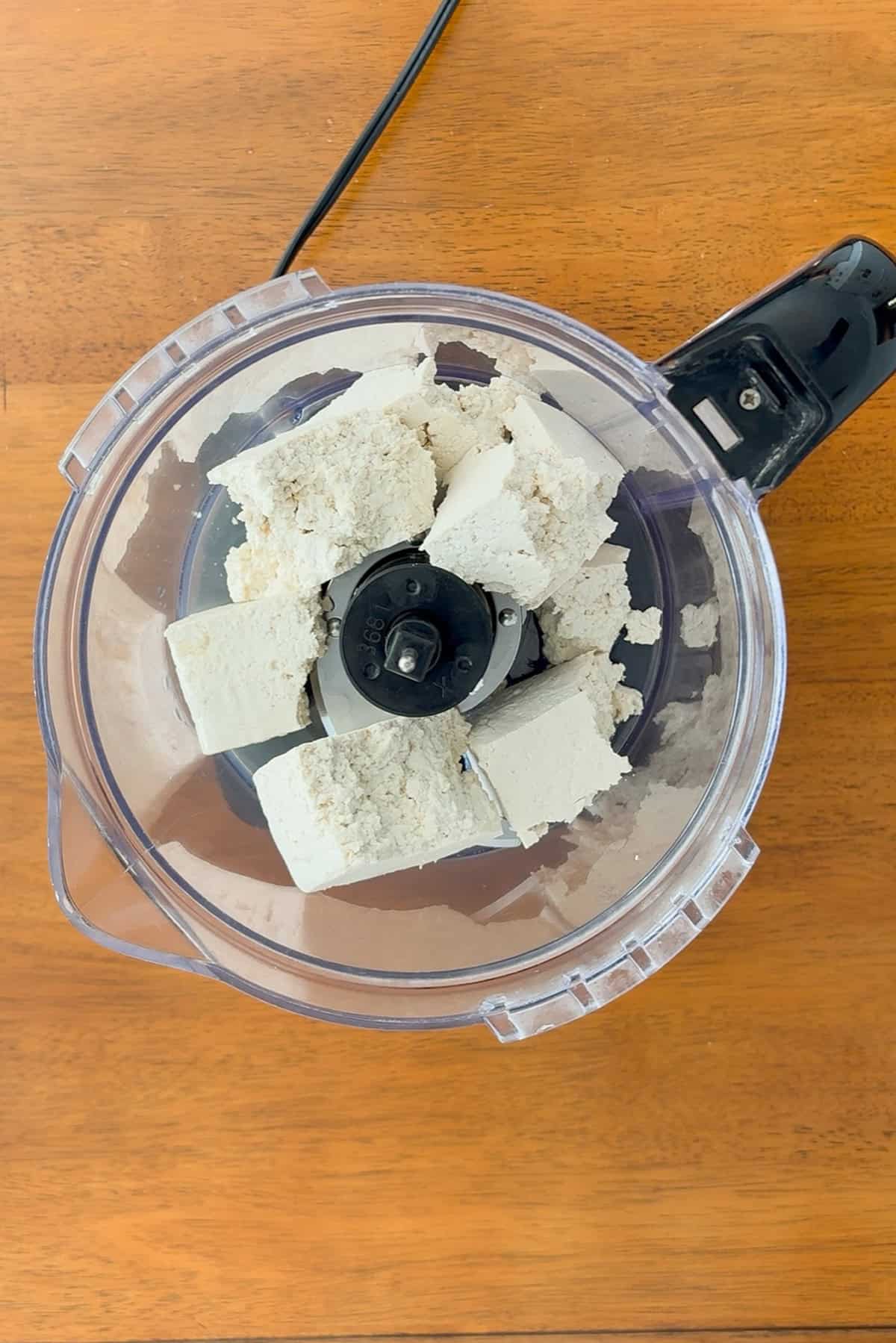 Tofu, broken into pieces and placed in a food processor.