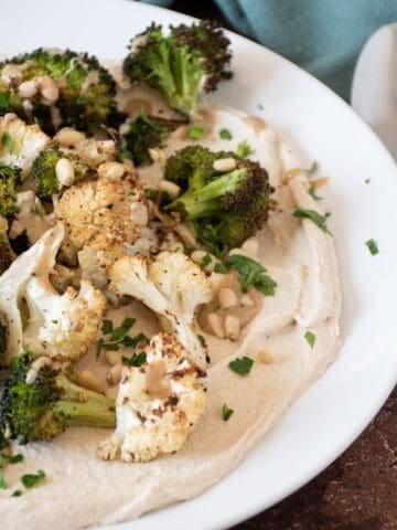 Roasted broccoli and cauliflower on a plate, over whipped tofu.