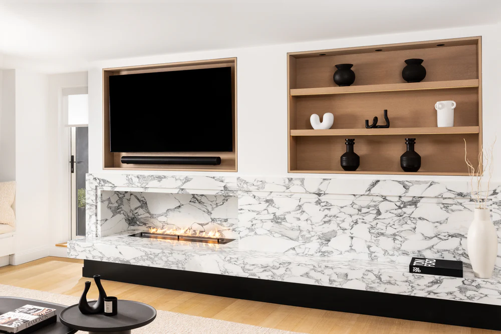 Living-room fireplace surround with bold gray and black veining on white stone.