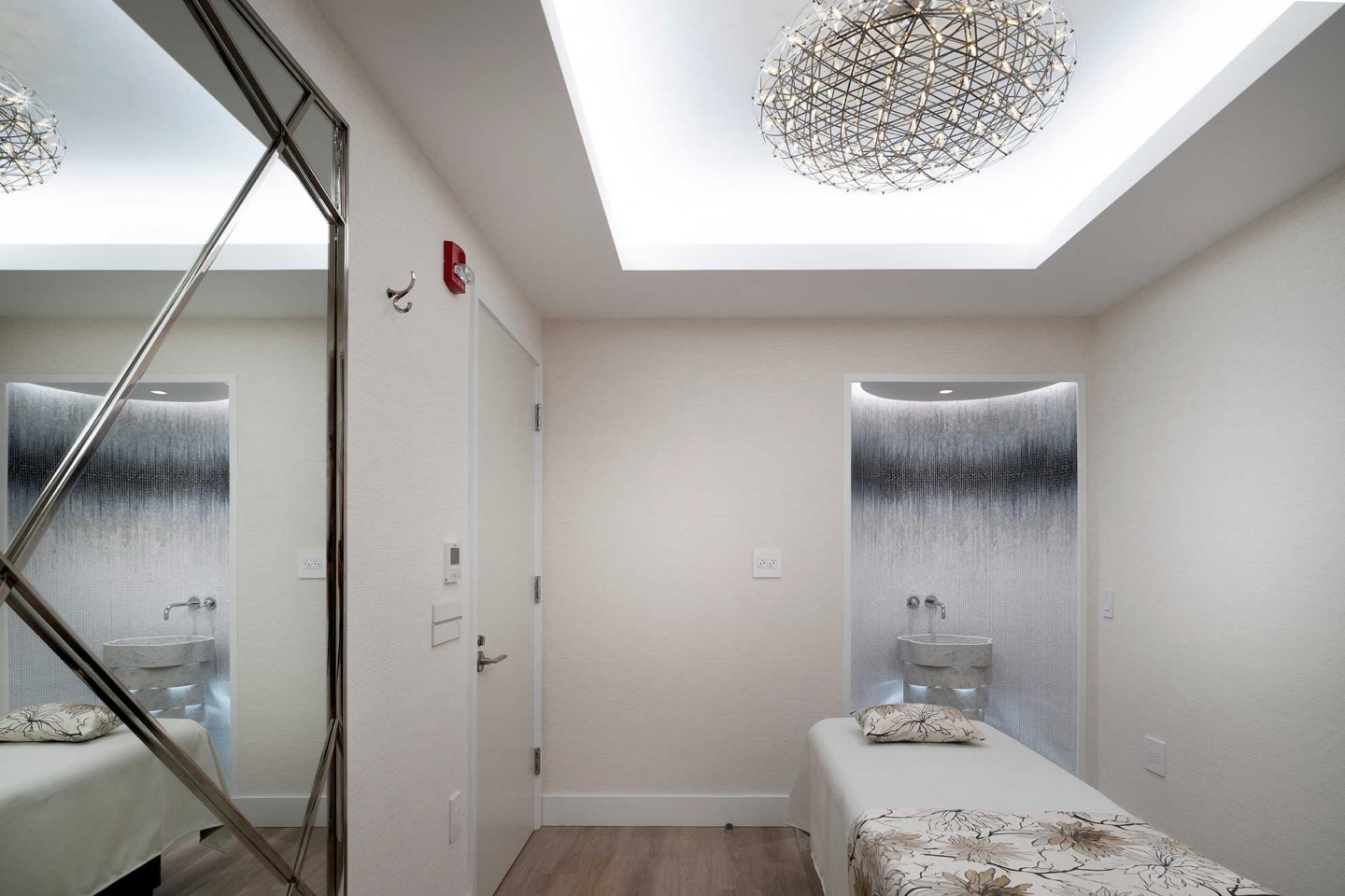 Spa treatment room with a curved illuminated accent wall and crystal ceiling light.