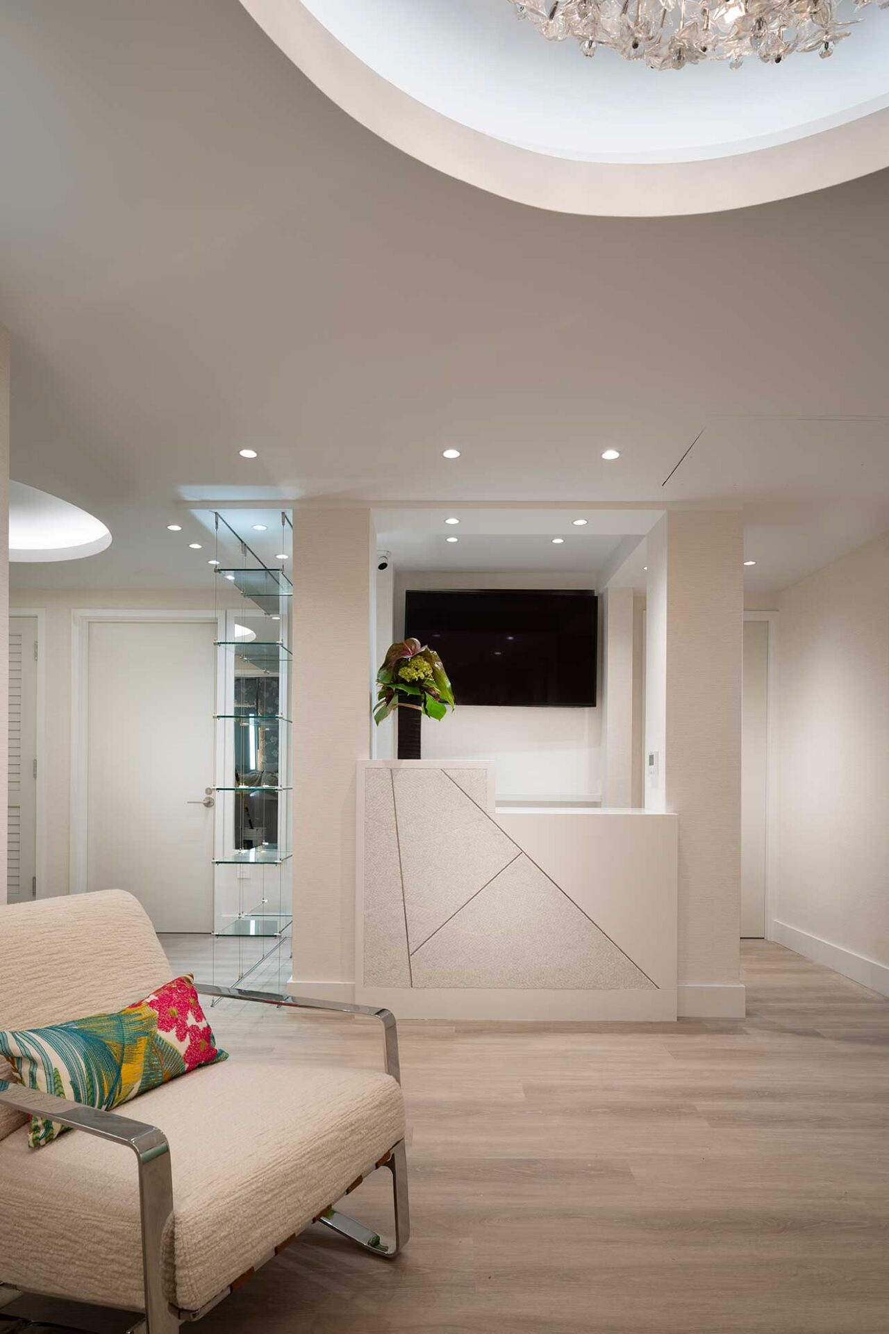 Spa reception area with pale flooring, a white counter and recessed ceiling lights.