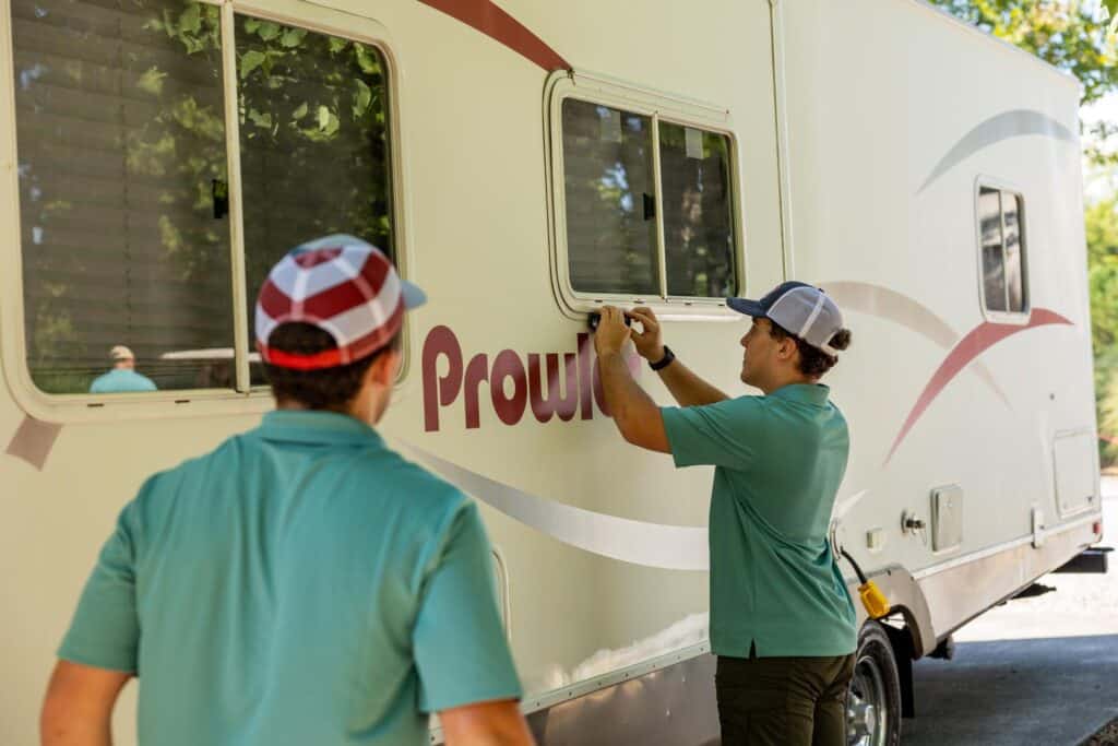 Two men painting a sign on a rv.