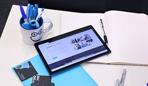 Dundee office workspace with tablet, pens, and blue-themed stationery.
