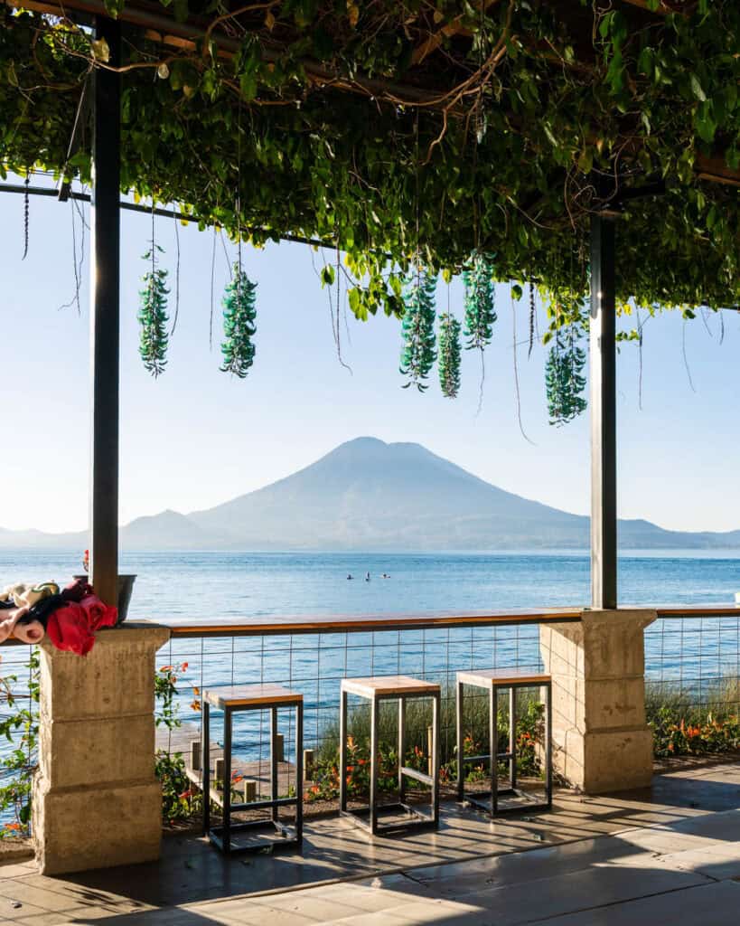 The view from the balcony of Free Cervesa hostel on Lake Atitlan in Guatemala with three paddle boarders enjoying the tranquil waters