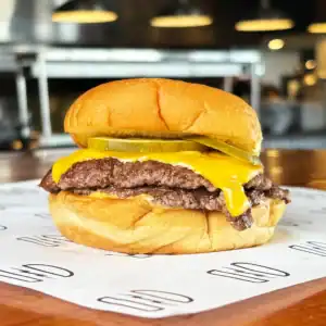 Juicy cheeseburger with pickles and melted cheese on a bun at Burger Rebellion.