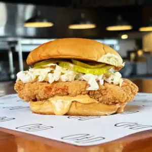 Crispy fried chicken sandwich with coleslaw and pickles on a bun.