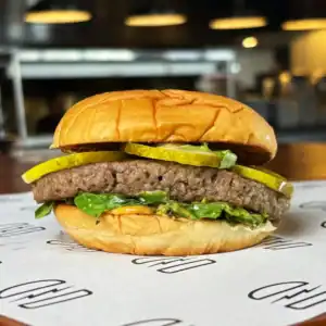 Juicy beef burger with pickles and lettuce in a soft bun at Burger Rebellion.