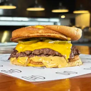 Juicy cheeseburger with pickles and mustard on a toasted bun at Burger Rebellion.