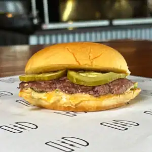 Classic burger with pickles, beef patty, and bun at Burger Rebellion.