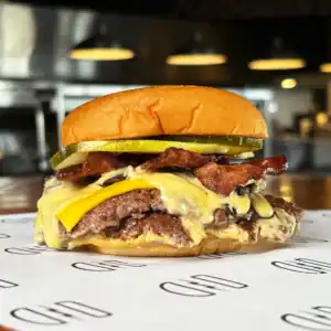 Juicy burger with bacon, pickles, cheese, and beef patty on a bun.