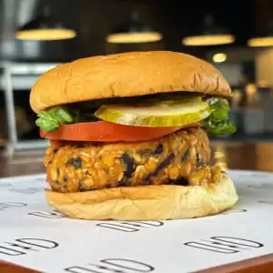 Vegetarian burger with veggie patty, lettuce, tomato, pickles in a bun.