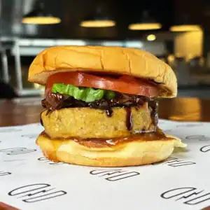 Gourmet veggie burger with tomato, lettuce, and sauce on a toasted bun.