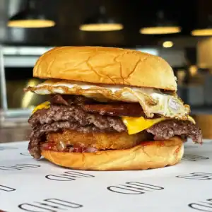 Juicy burger with fried egg, cheese, bacon, and beef patty in a bun.