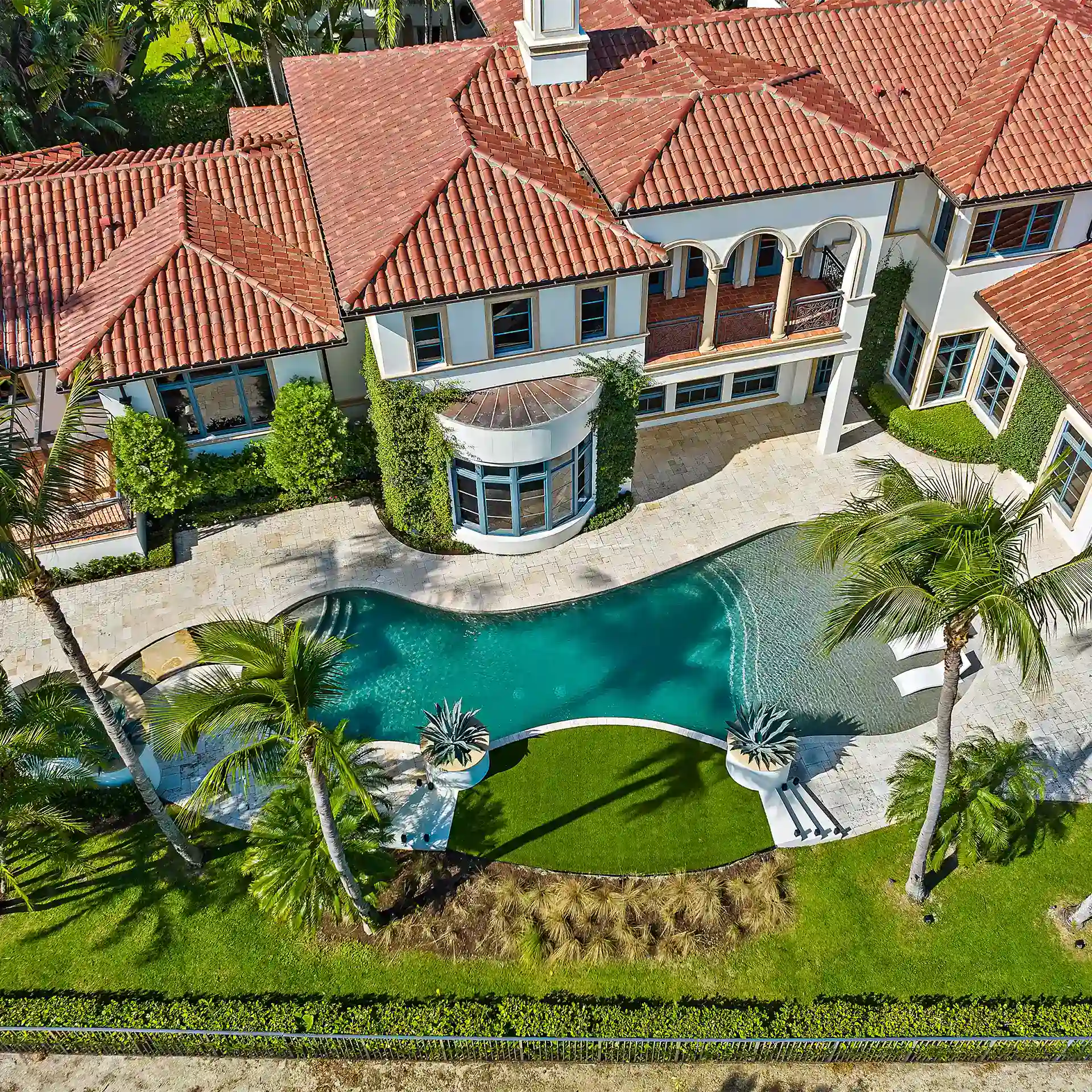 Captivating aerial image of a luxury New Mediterranean style property, featuring a glistening pool and surrounded by exquisite landscaping.