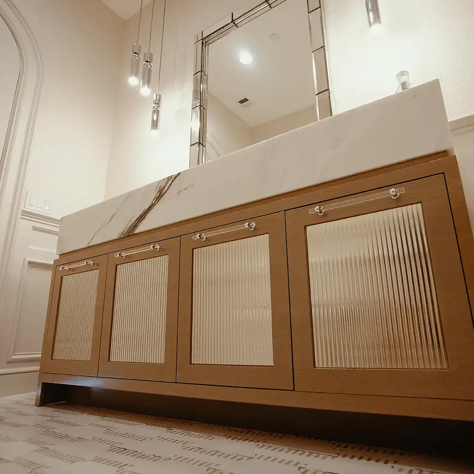 Custom-stained ash doors with inset fluted architectural mirrors topped with an 8-inch mitered Paonazzo Marble