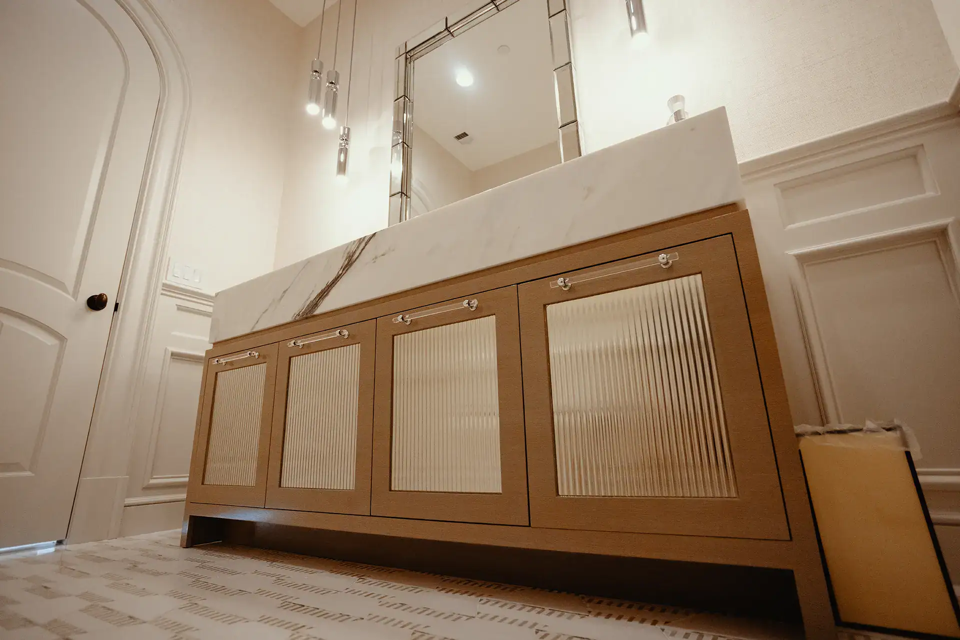 Custom-stained ash doors with inset fluted architectural mirrors topped with an 8-inch mitered Paonazzo Marble