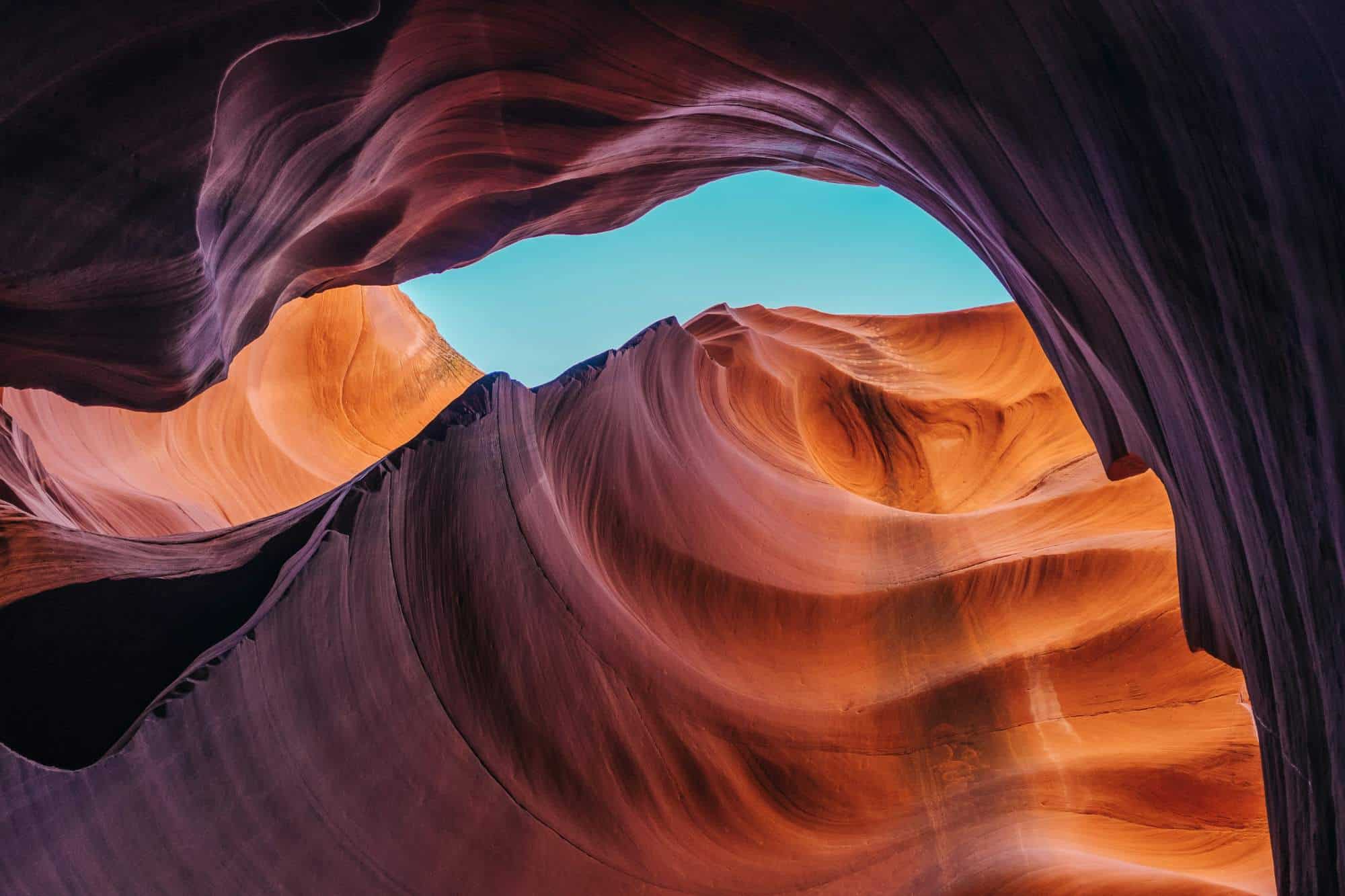 Beautiful slot canyon with colorful rock formations and a clear blue sky overhead.