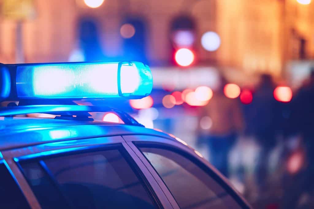 Blue police car emergency lights flashing at night, law enforcement in action.