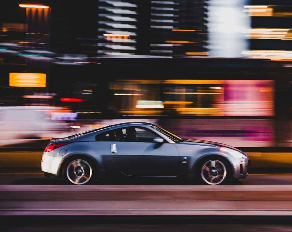 Luxury sports car in motion on urban street at night, showcasing speed and style.