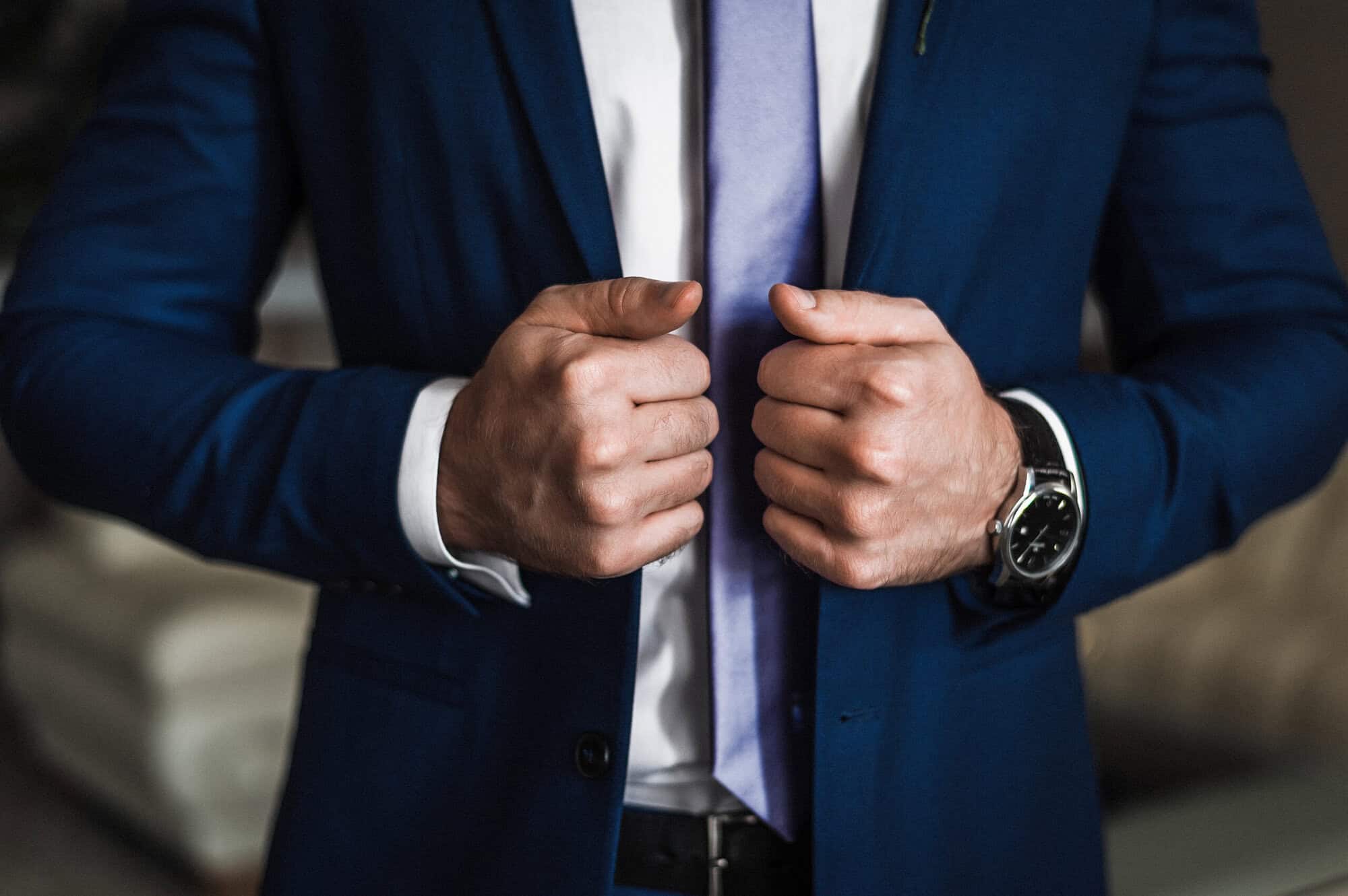 Business professional adjusting suit jacket for confidence.
