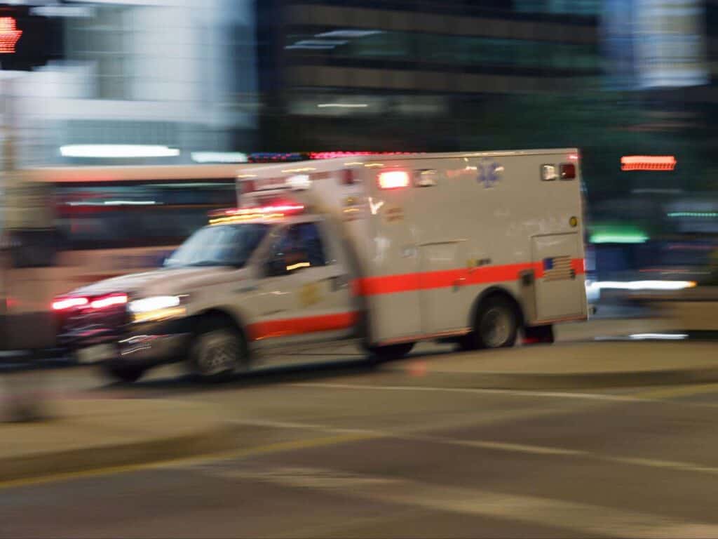 Ambulance driving quickly through city streets at night.