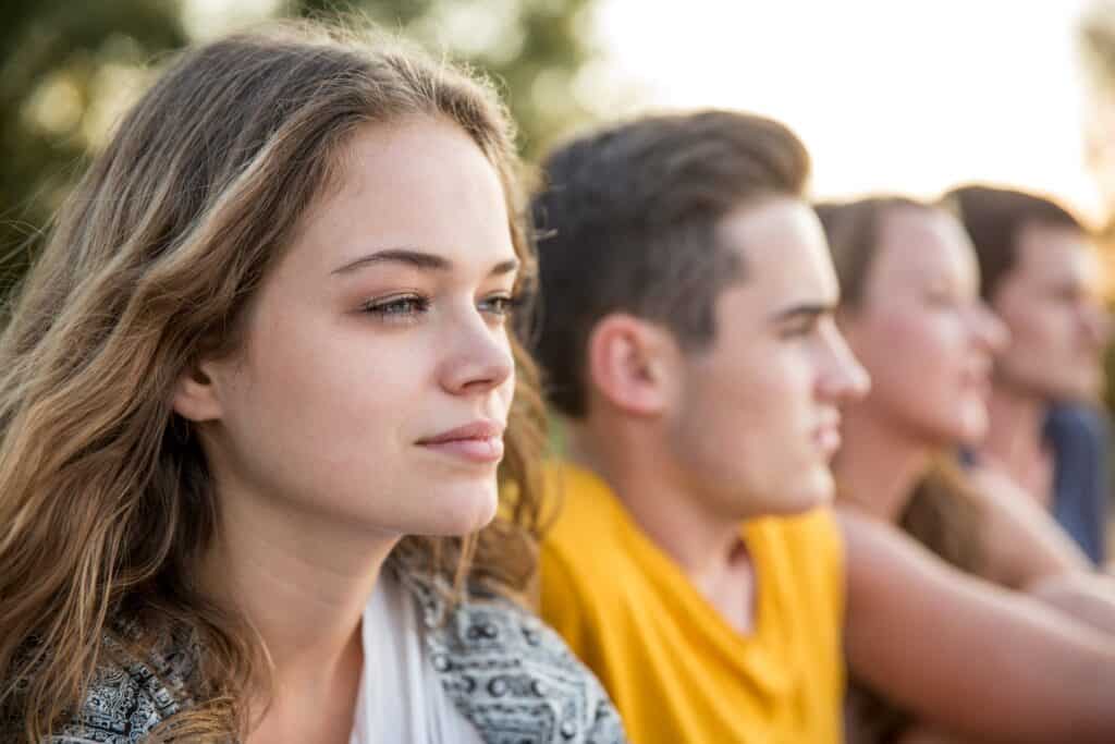 Teenagers listening attentively outdoors, symbolizing youth engagement and community involvement in.