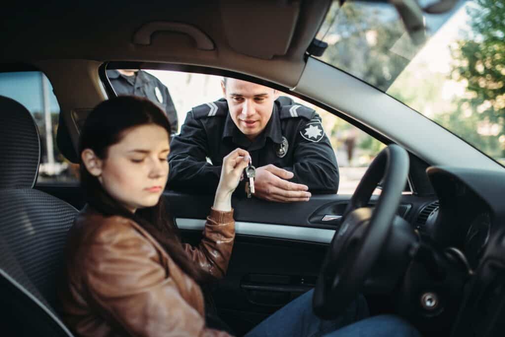 Police officer speaking to woman inside a car during a traffic stop.