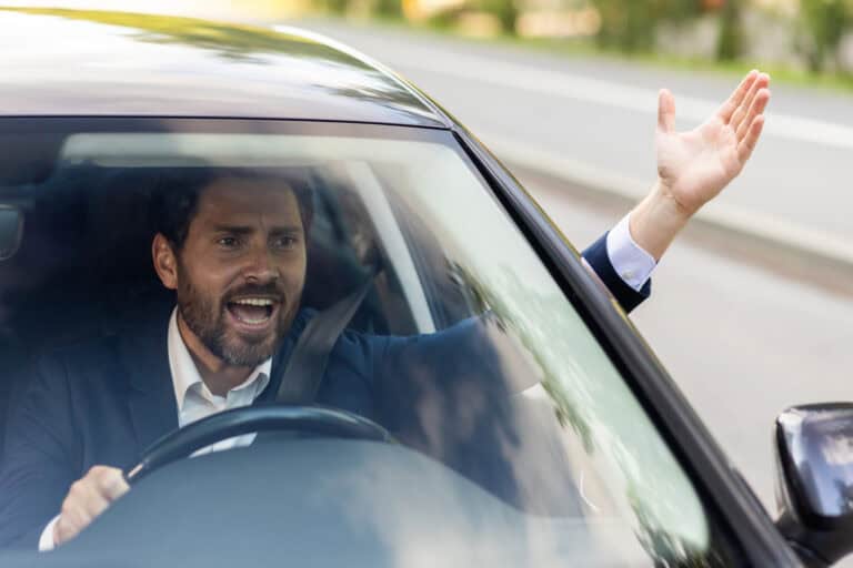 Man angry in car during road rage incident, aggressive driving, legal consequences.