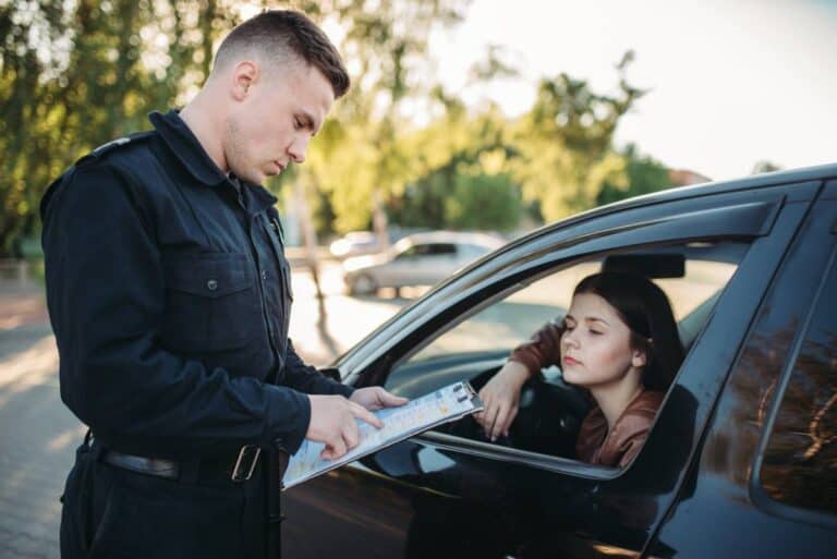 Police officer inspecting driver's license during traffic stop in Arizona.