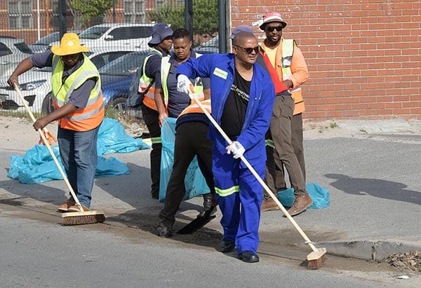 (Front) Mayoral Committee Member for Urban Waste Management, Alderman Grant Twigg cleaning the street with an EPWP cleansing team.