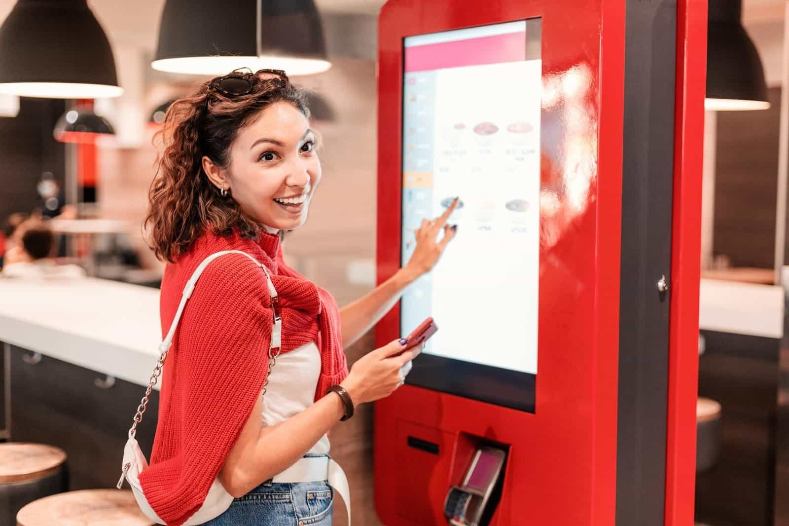 Woman ordering food at kiosk.