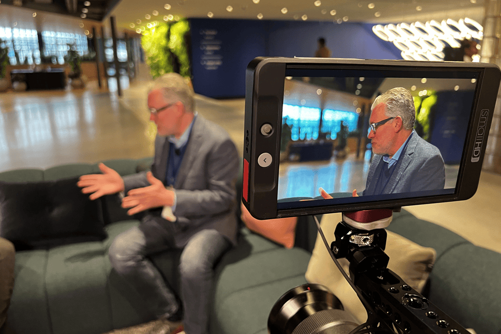 Clip of Chris Hood, AI Keynote Speaker being recorded on camera during an interview at a modern indoor venue, emphasizing professional video recording, interviews, and digital content creation.