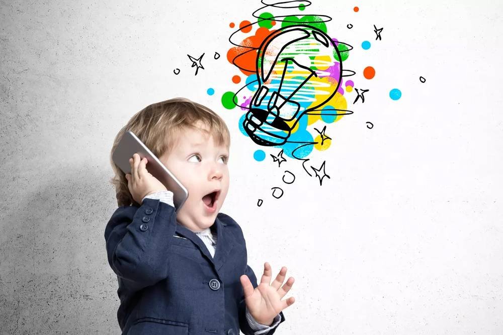 Colorful doodle of a light bulb with paint splashes and stars above a surprised young boy talking on a smartphone, representing creativity and innovative ideas.