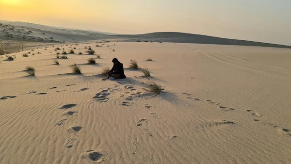 Person sitting alone in desert sand symbolizing emotional disconnection and isolation after trauma