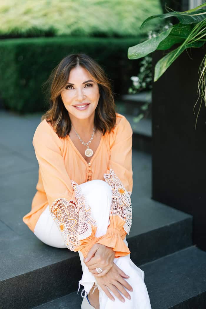Cindy Benezra in an orange shirt on the steps of her home, dressing with intention for fall
