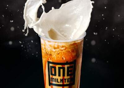 A cup of milk tea with a splash of milk.