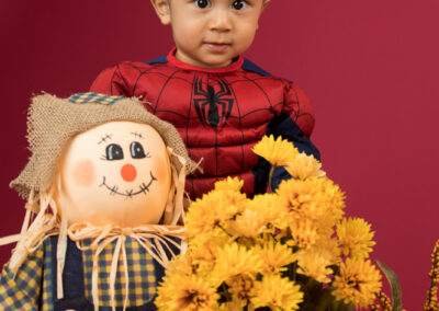 A boy posing with a scarecrow.