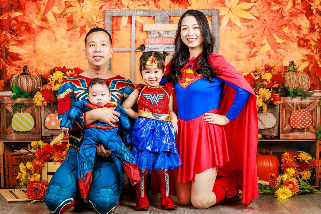A family posing for a photo in superman costumes.