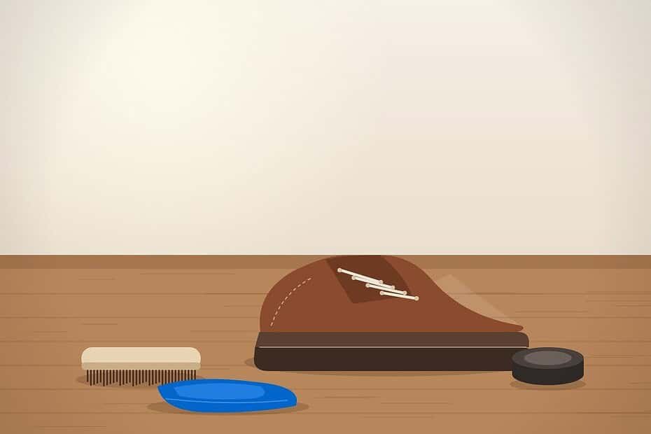 Shoe lift maintenance supplies: a modified shoe with a built-in sole lift on a wooden workbench next to a brush, polish tin and blue microfiber cloth