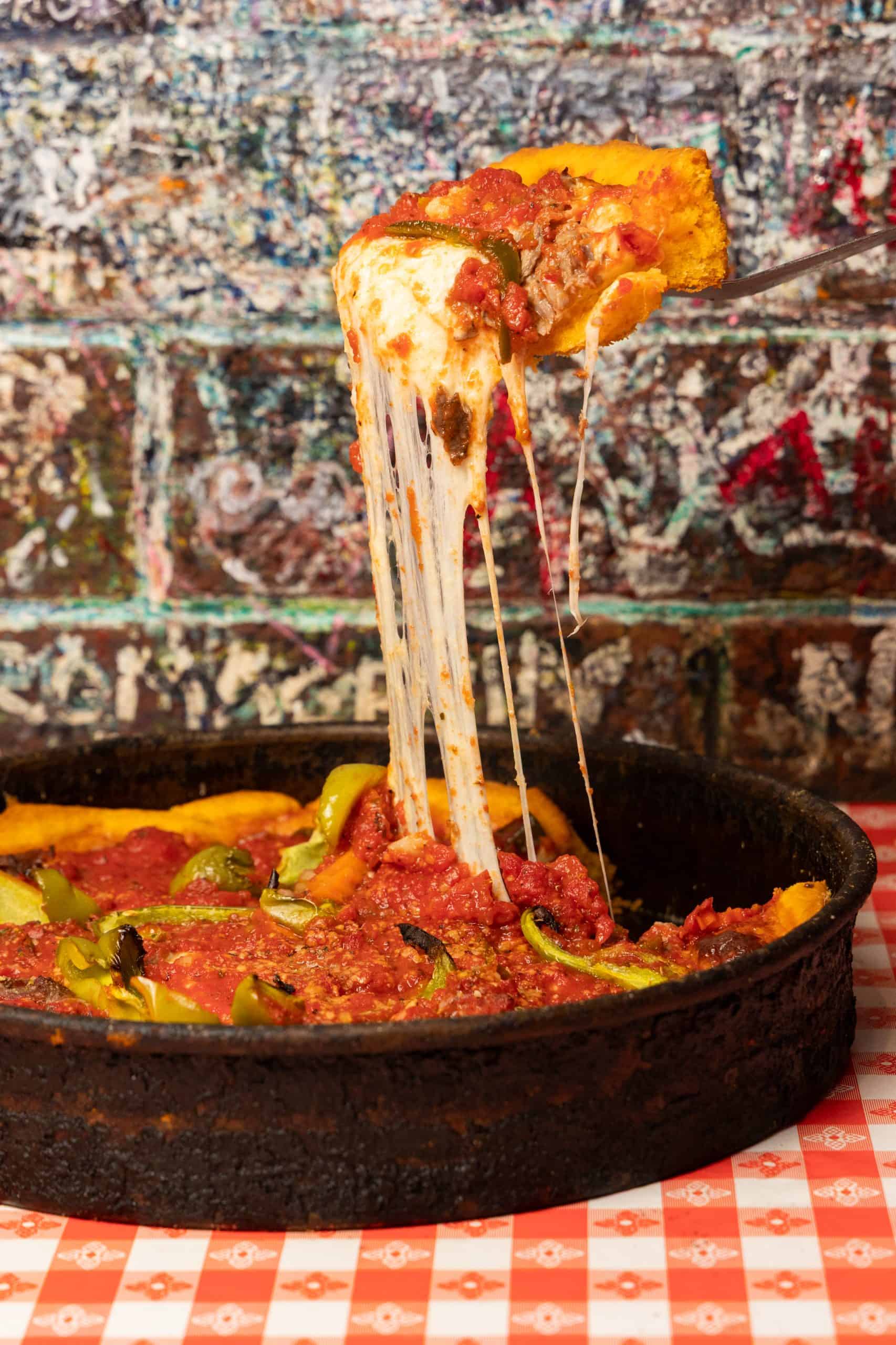 Deep-dish pizza slice with stretching cheese at Gino's East