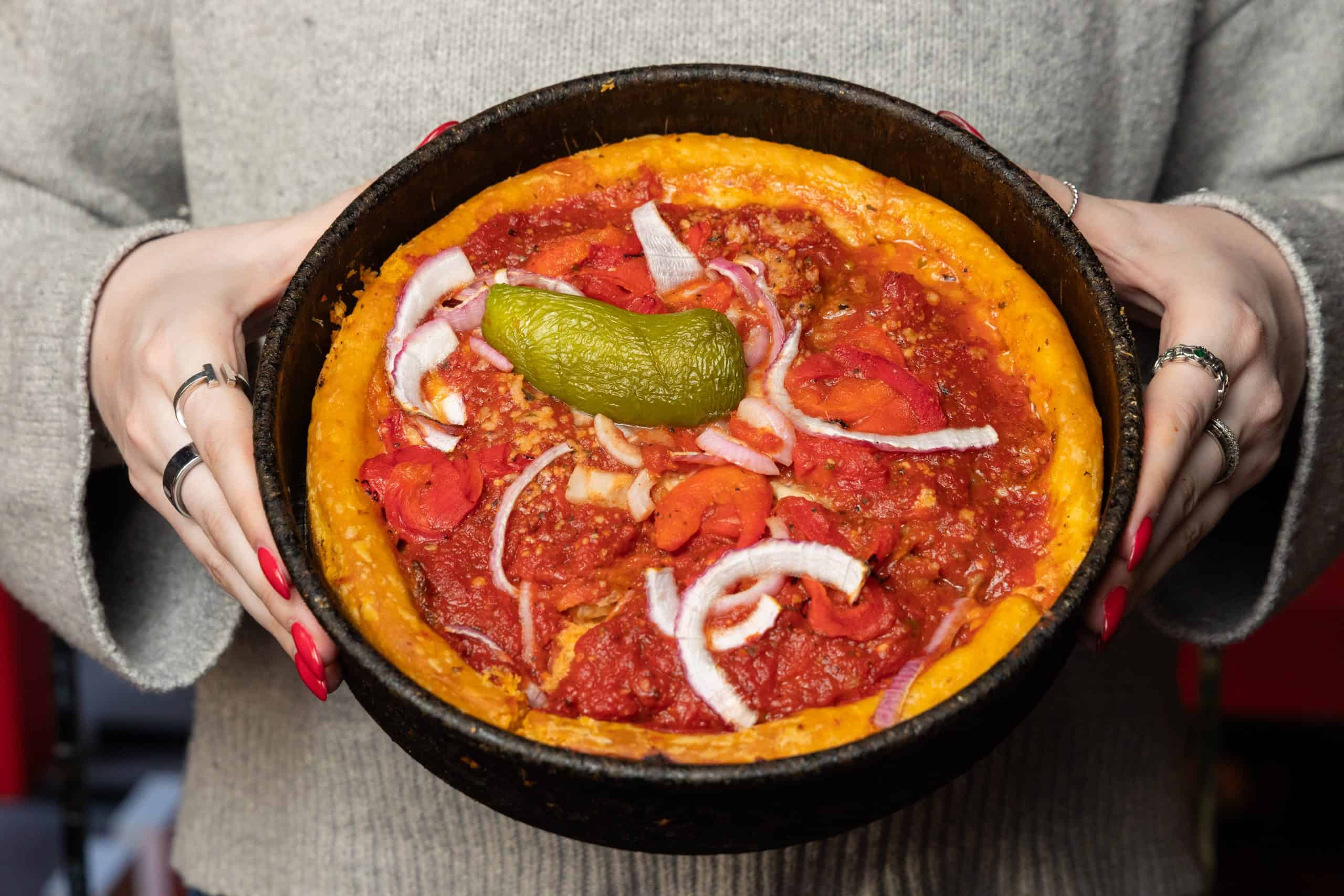 Deep-dish pizza with tomato sauce and peppers in a cast iron pan