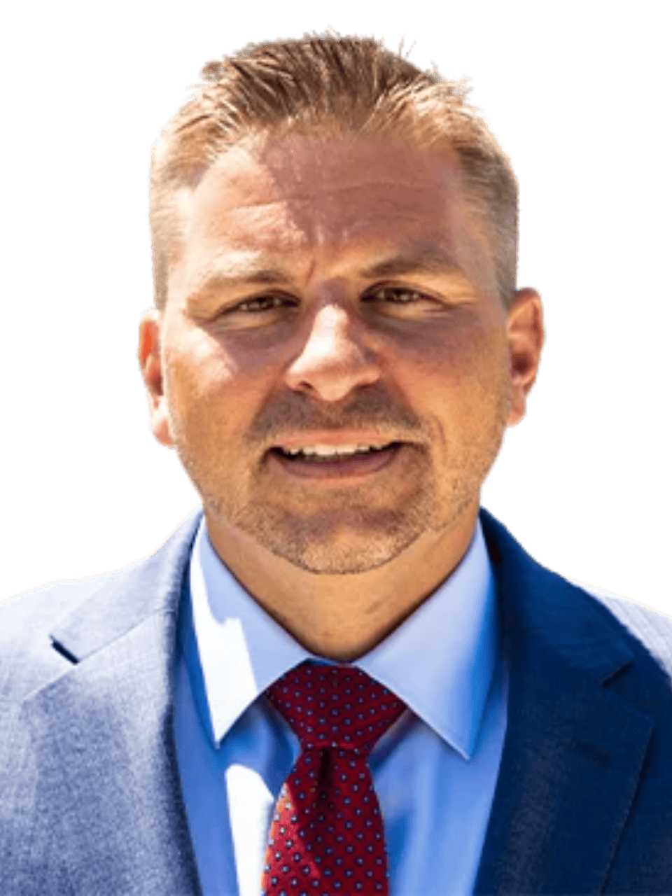 Professional man in a blue suit smiling outdoors with a blurred background.