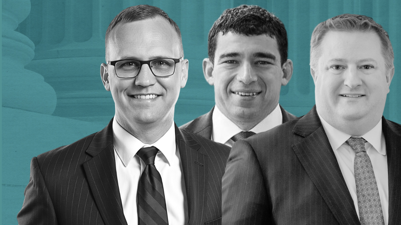 Three professional men in suits smiling for a business photo.