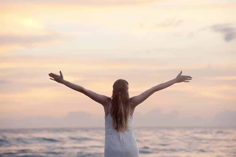 A woman enjoying a serene sunset on Unawatuna Beach, Sri Lanka, depicting peace and freedom.
