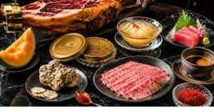 A flat-lay arrangement of the most expensive foods in the world including caviar, white truffle, saffron, and Wagyu beef on a dark marble surface