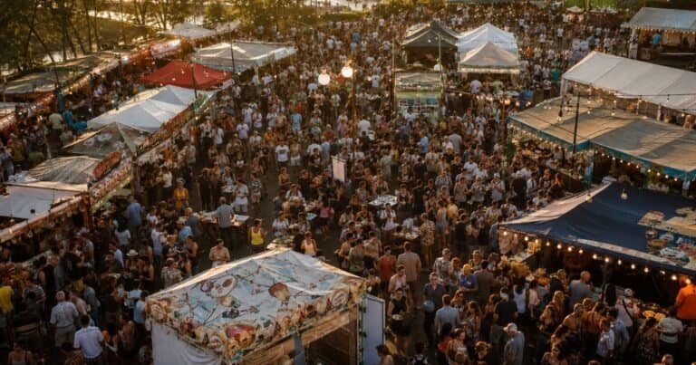Crowds enjoying food festivals around the world at a colorful outdoor street market at golden hour.
